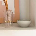 Bowl on shelf with glass vase in background