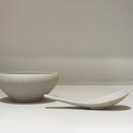 Bowl and spoon set side by side on white surface