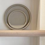 Handcrafted stoneware drum-edge plates stacked on shelf
