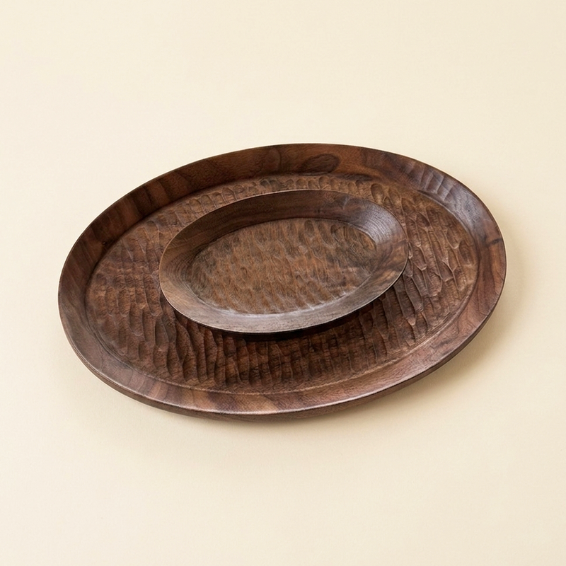 Three nested dark walnut oval trays with carved textures