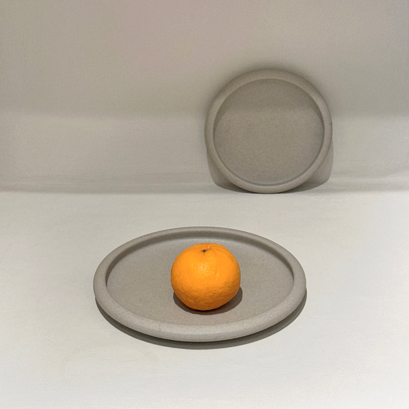 Drum-edge plate with orange on white surface