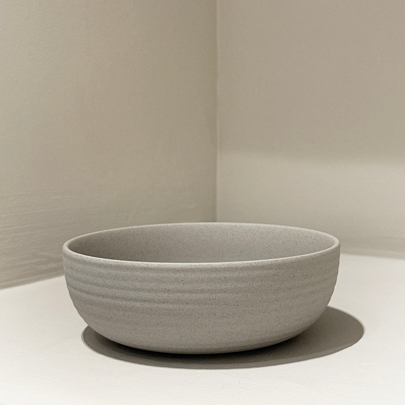 Handcrafted stoneware ribbed breakfast bowl on white surface