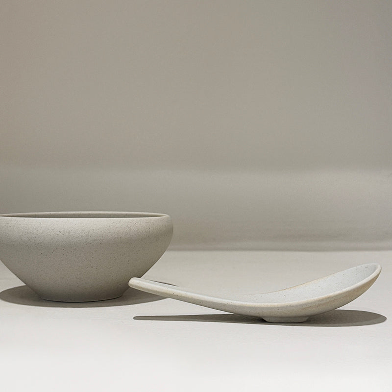 Bowl and spoon set side by side on white surface