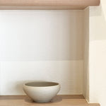 Stoneware bowl on wooden shelf with white wall