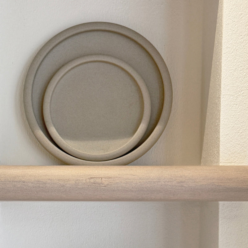 Handcrafted stoneware drum-edge plates stacked on shelf