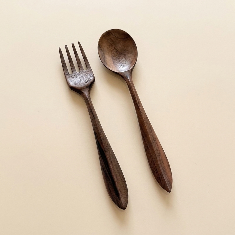 Dark walnut wood fork and spoon set on a neutral background
