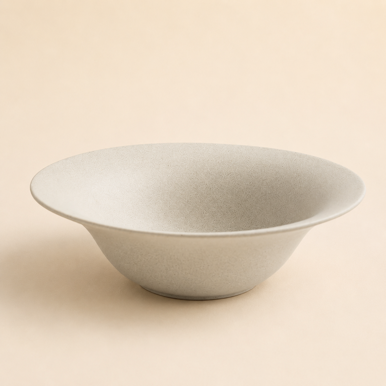 Wide shallow speckled cream stoneware bowl with a flared rim