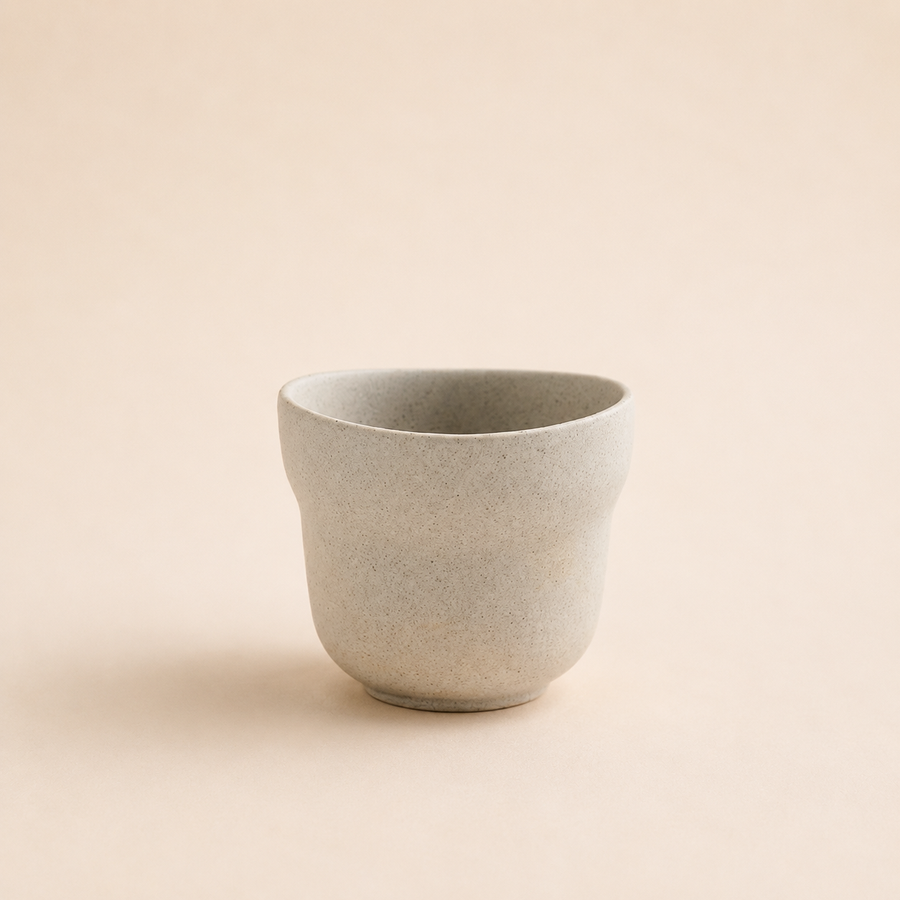 Speckled cream stoneware cup with a gently flared rim
