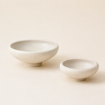 Two speckled cream stoneware pedestal bowls in large and small sizes