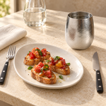 Pebble titanium cup beside bruschetta and black-handled flatware